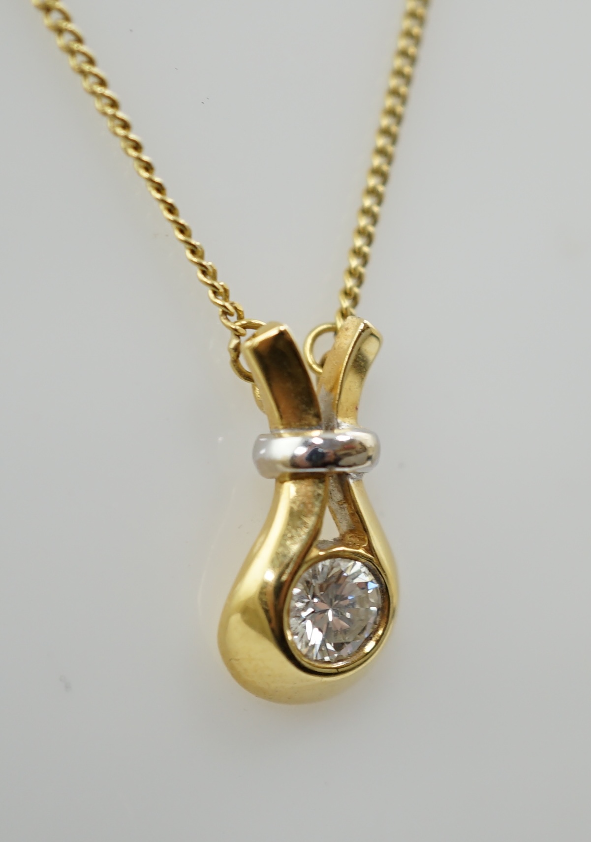 A modern 18ct gold and solitaire diamond set pendant, on an 18ct gold fine link chain